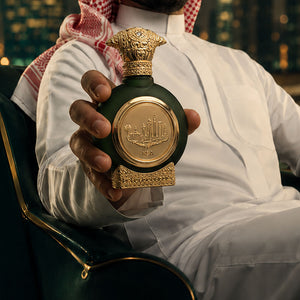 Man in traditional gcc dress holding KSA unisex perfume bottle 75ml against city lights - best unisex perfume
