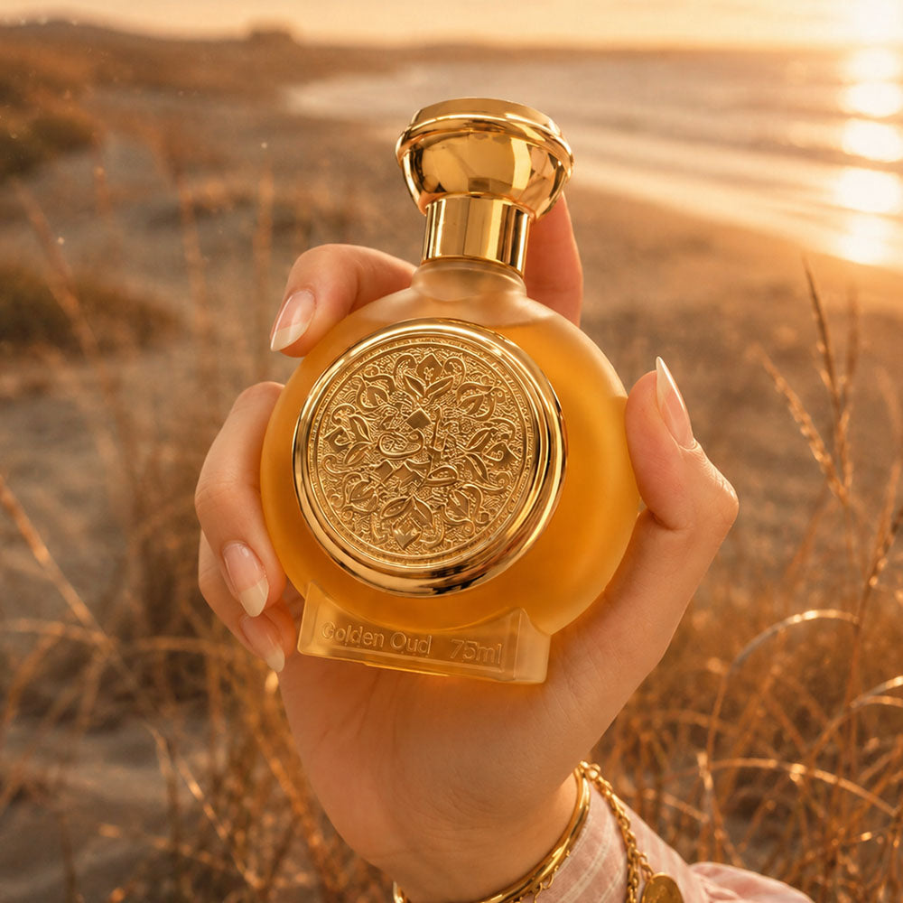 Hand holding GOLDEN OUD unisex perfume bottle 75ml at sunset beach, oud gold perfume