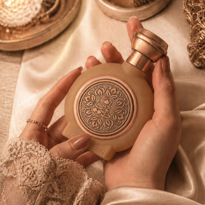 Hands holding TAIF 19 unisex perfume bottle 75ml - caramel fancy perfume bottle with caramel embossed taif al emarat logo - long-lasting leather perfume