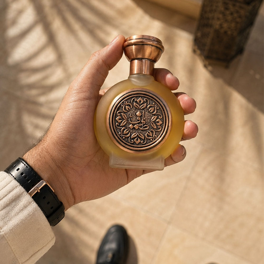 Hand holding TAIF 05 unisex perfume bottle 75ml on tiles, sandal perfume
