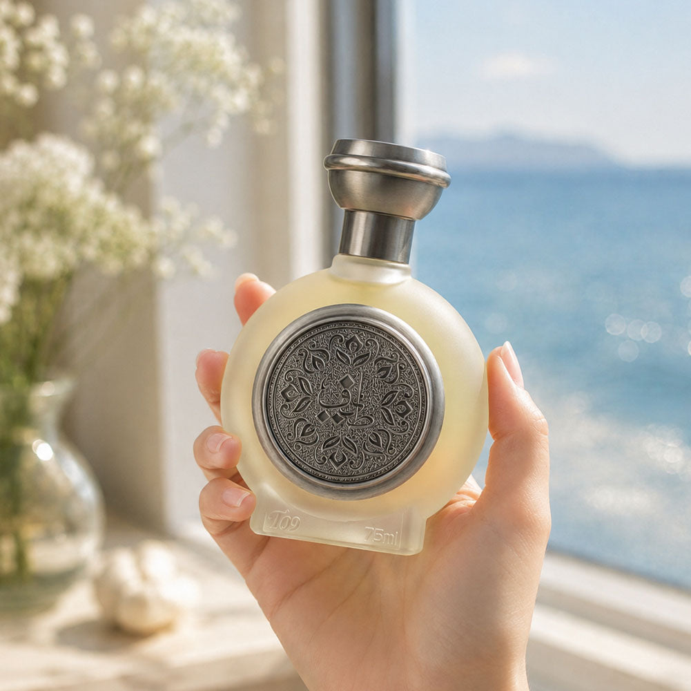 Hand holding TAIF 09 men's perfume bottle 75ml by ocean window, best fragrances for men