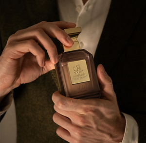 Hands holding V02 unisex perfume bottle 75ml from taif al emarat perfumes in dim light - oud perfume dubai