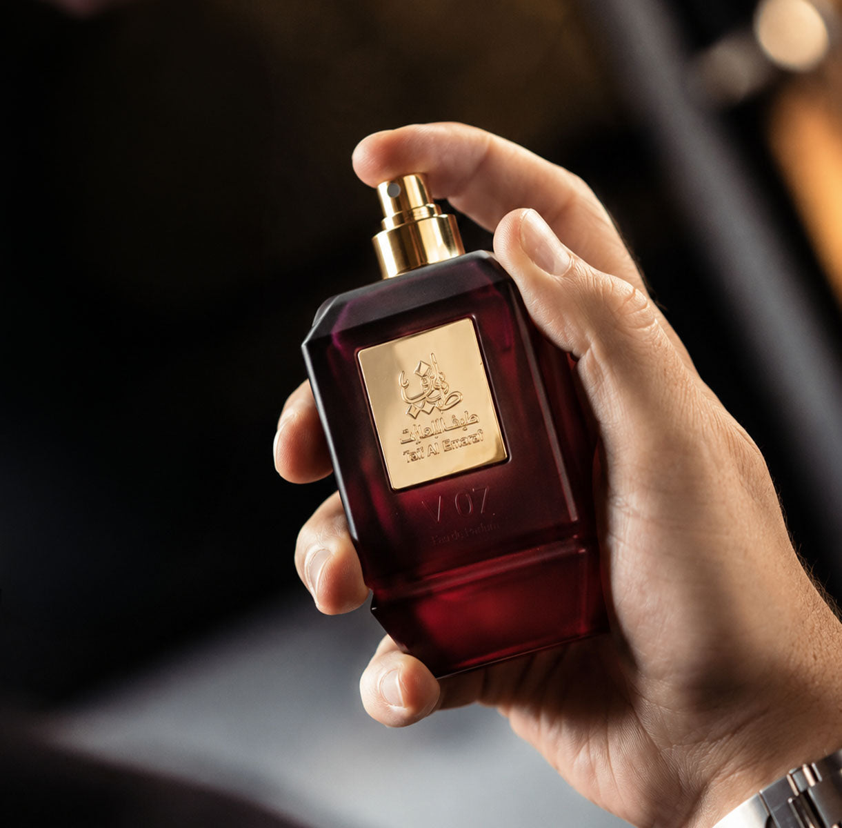 Hand holding V07 unisex perfume bottle 75ml about to spray - long lasting strawberry fragrance in dubai