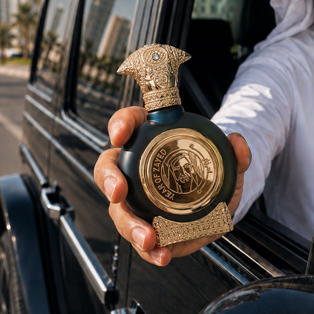 Hand holding YEAR OF ZAYED perfume bottle 75ml from taif al emarat perfumes, throw car window - best tobacco fragrance