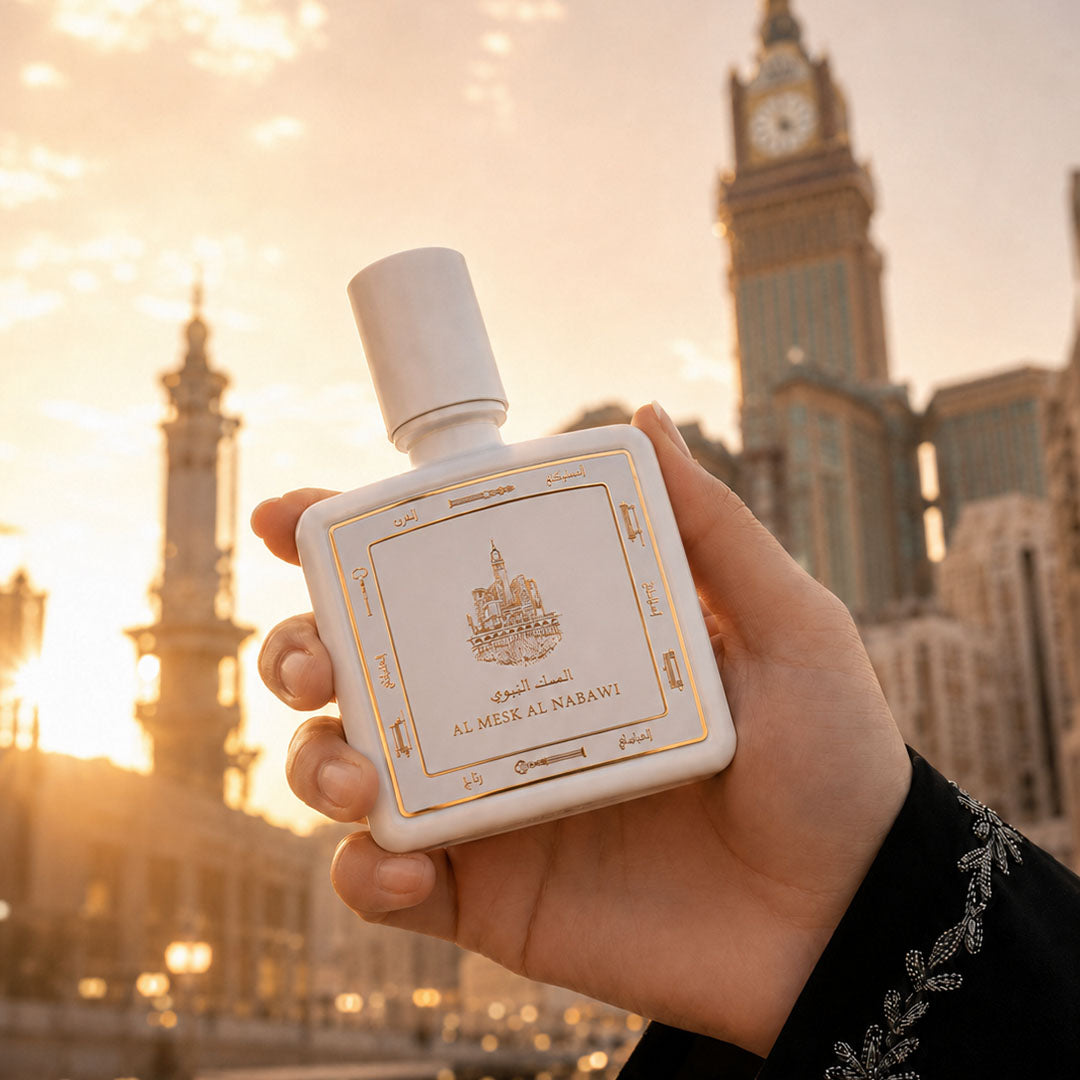 Hand holding Al Mesk Al Nabawi perfume bottle 80ml from taif al emarat perfumes before mecca city  clock tower - a rich rose musk perfume