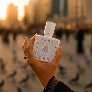 Hand holding Al Rawda perfume bottle 80ml from taif al emarat on a sunset view in the background - strong amber perfume